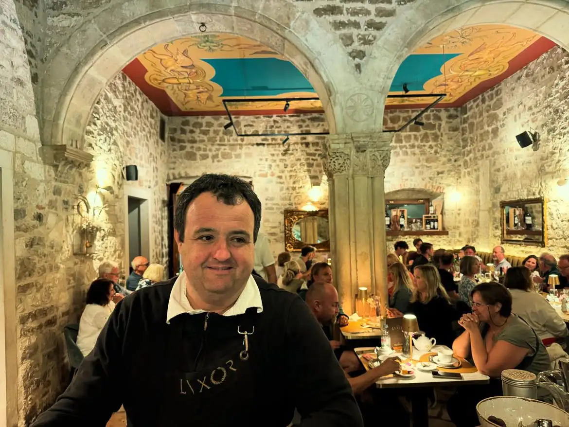 Gost za stolom u Lvxoru, iza njega antički stupovi