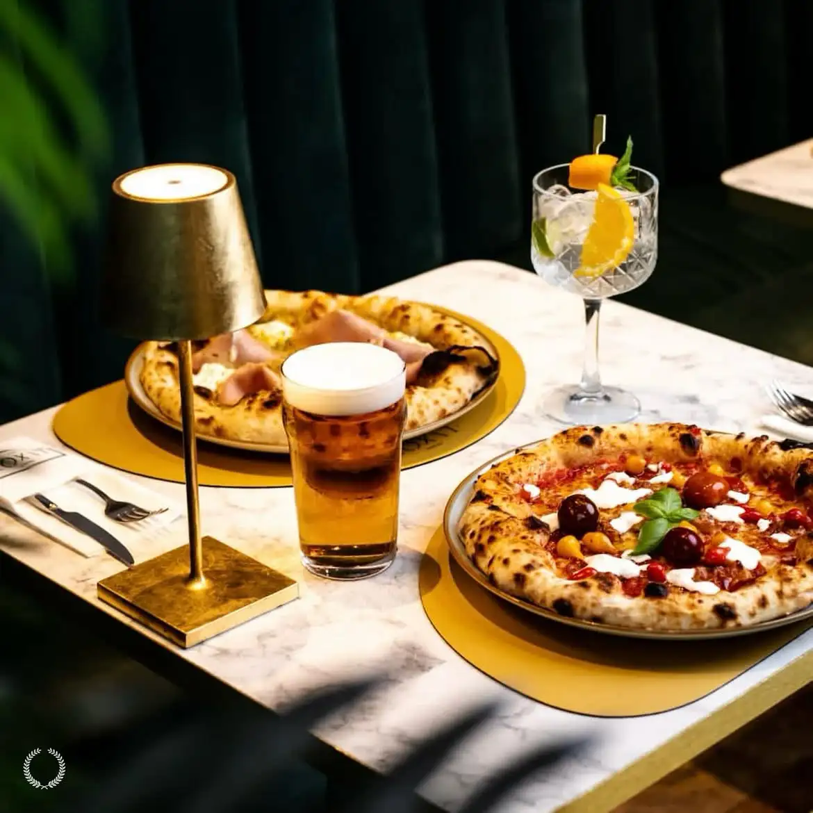 Dvije pizze, pivo i koktel na stolu Lvxora