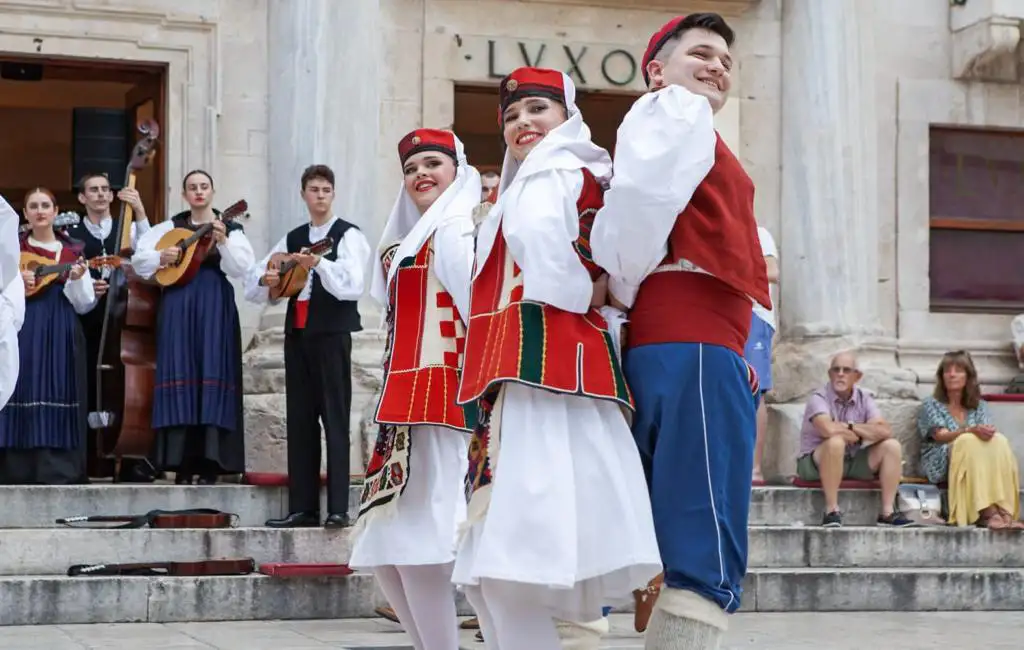Plesači u nošnjama pred natpisom Lvxor