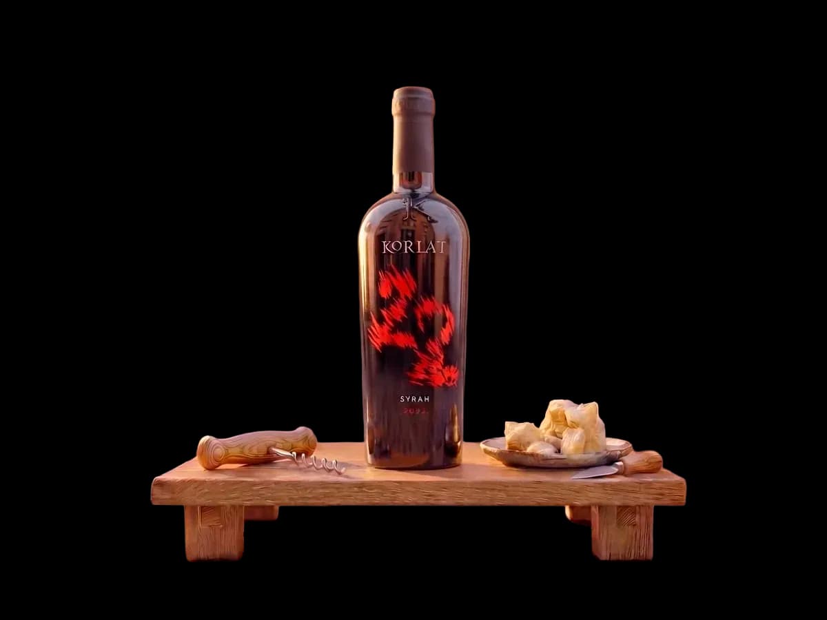 A bottle of Korlat Syrah from Benkovac on a wooden stand, with a corkscrew and a plate of cheese